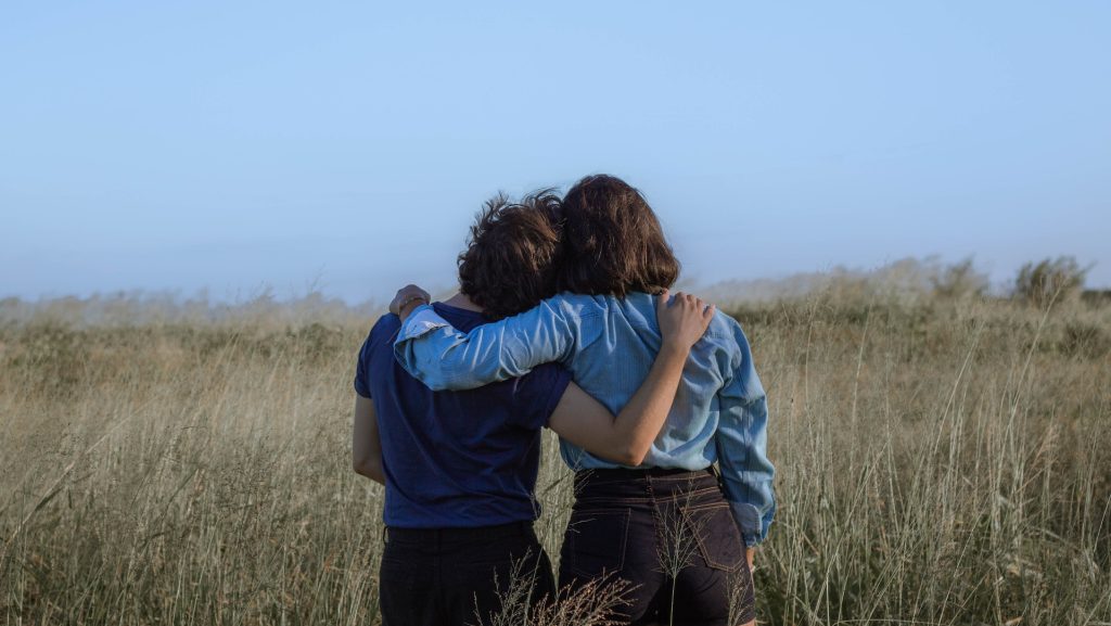 Friends hugging each other to reconcile while contemplating a field.